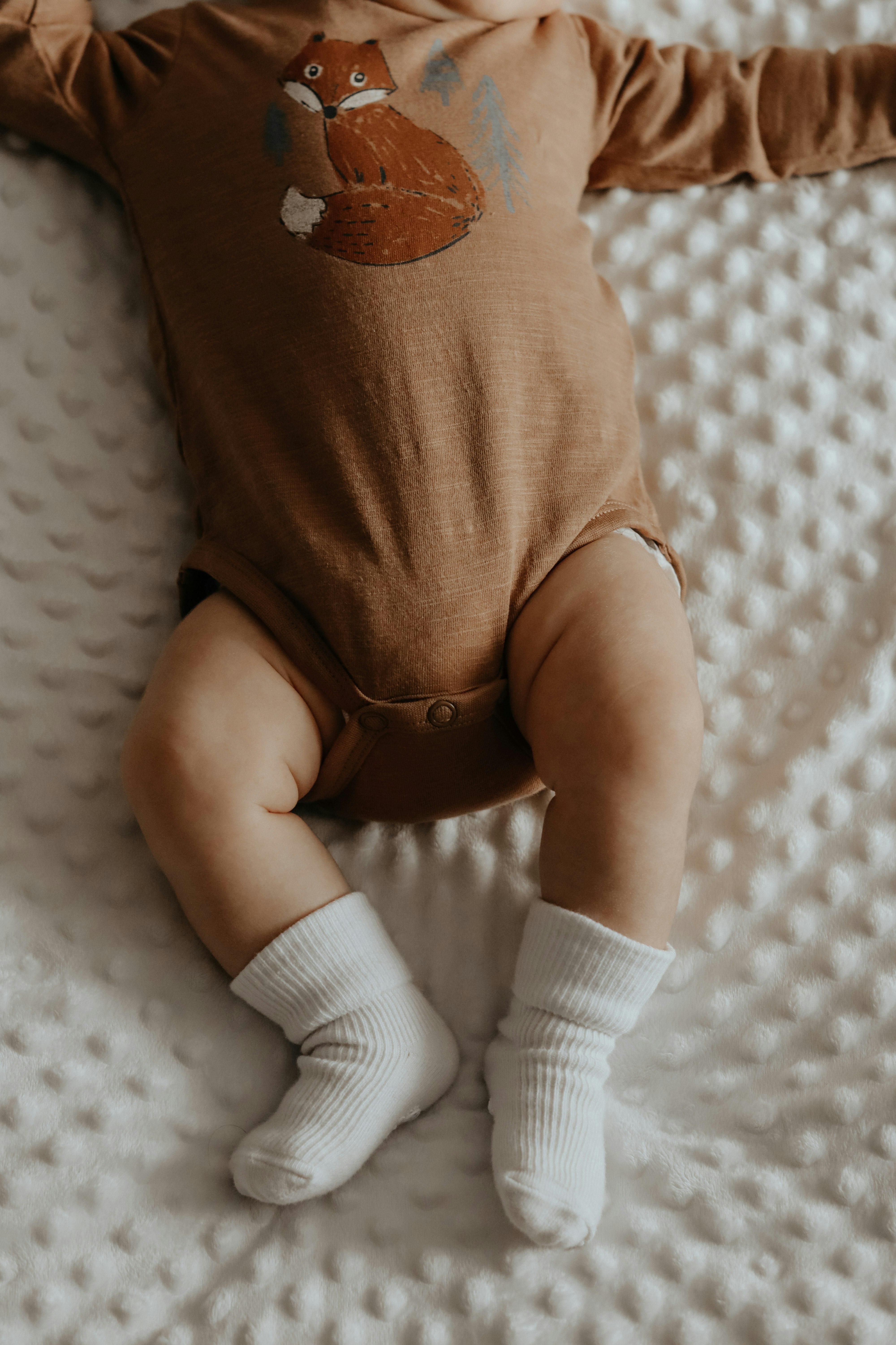 baby in white onesie and white socks